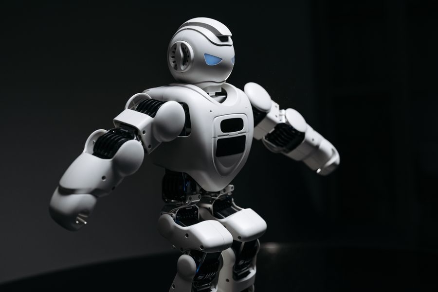 Robô humanoide branco em movimento sobre fundo escuro