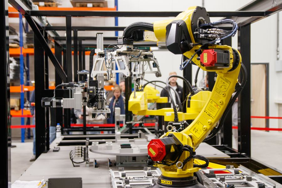 Braço robótico industrial amarelo em operação numa linha de fabricação